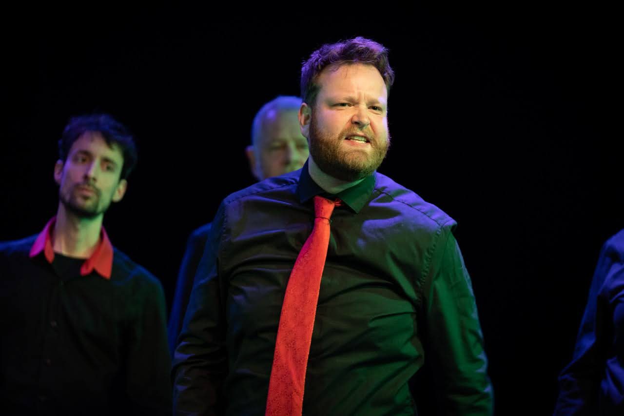 Jelle Gulmans met rode das in een ensemblescène